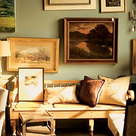 Oil paintings and etchings of the English countryside accompany an English antique pine bench at RJA Design