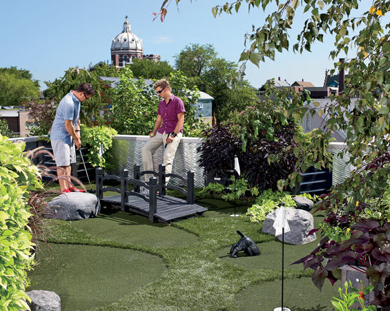 Kolacz (seated, with his partner, David Kroeger) at the five-hole miniature golf course on the roof of their building
