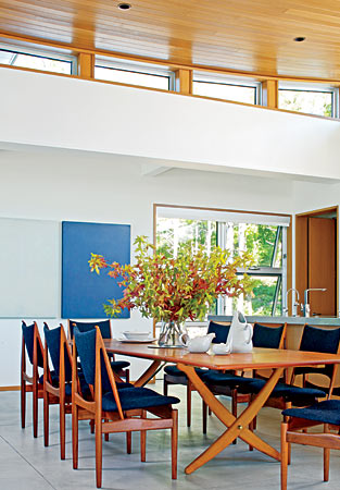 A Hans Wegner table is the focal point of the open-plan dining room/kitchen in a Michigan getaway. From the upholstery on the chairs to paintings by Carol Dolan, most of the colors in the space were dictated by what the owners could see out their windows—namely, Lake Michigan.