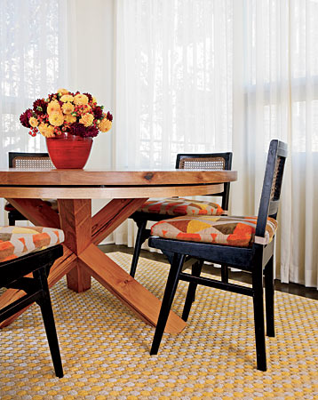 Vintage chairs from The Golden Triangle and a custom table accommodate both family meals and entertaining in a Wicker Park dining room, where the combination of sleek lines, warm colors, and a richly textured rug create a welcoming environment.