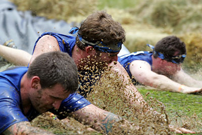 Three Geneva Gladiator Assault Challenge participants in the mud