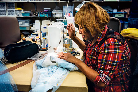 A seamstress adjusting the costume for a snow fairy