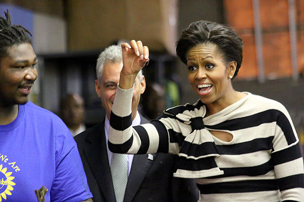 First Lady Michelle Obama picks up a worm at Iron Street Urban Farm on the South Side as worker Jeremy Jackson and Mayor Rahm Emanuel look on.