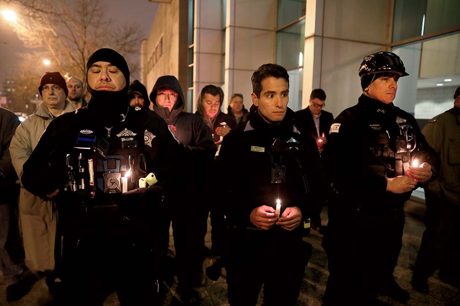 Police offers holding candles outside at a vigil for Paul Bauer