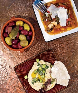 Taxim’s mezedes of piperies (roasted peppers with capers and kefalograviera; revithia (puréed chickpeas with sautéed green chickpeas); and marinated olives