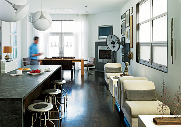 A large island topped with gray limestone separates the food-prep area of the kitchen from lounge seating—two sets of Stendig armless chairs from the 1970s. A chunky wood dining table accommodates larger groups.