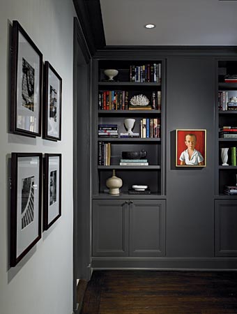 In a Beaux Arts apartment on the Gold Coast, the designers at Hudson Home turned a utilitarian hallway separating public spaces from private into a dramatic focal point by converting it into a warm gray library (Benjamin Moore Kendall Charcoal); the portrait, with its dominant white and red tones, is striking against this background.