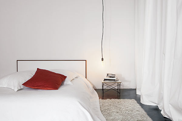 This ultra-spare retreat distills the bedroom to its essence: a place for a bed. With a low-profile vintage Knoll headboard as the main attraction and a predominantly white color scheme, the effect is mellow and restful. A low-hanging Edison-style bulb draws attention to the loft’s high ceiling.