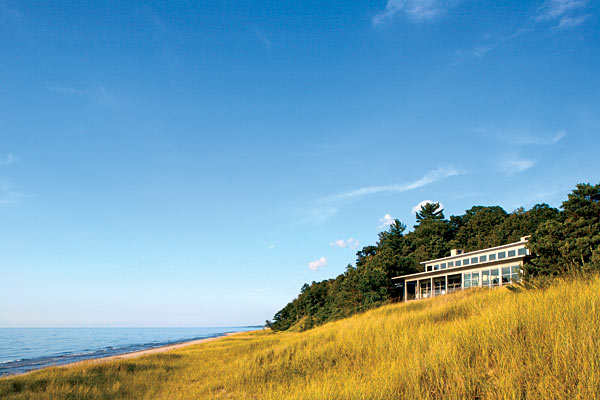 Architect Laurence Booth, who designed this lakefront house, says he likes the way “its crisp rectilinear shape plays against the curvilinear dunes and the swaying pine trees.”