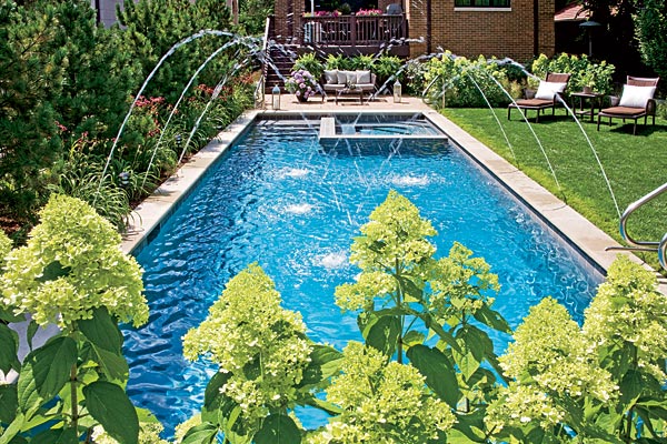 The spray of jets from just outside its rim lets the pool serve double duty as a place to swim and as a decorative water feature. Daylilies and other perennials line one side of the pool.