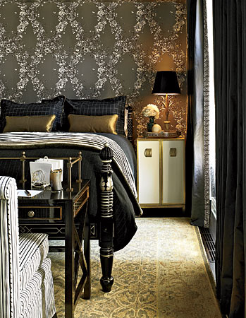 A bedroom decorated in dark, floral graphic wallpaper