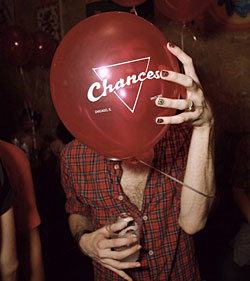 Party goer holding balloon with the Chances logo imprinted on it.