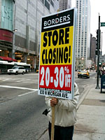 A worker holding a 'Store Closing' sign