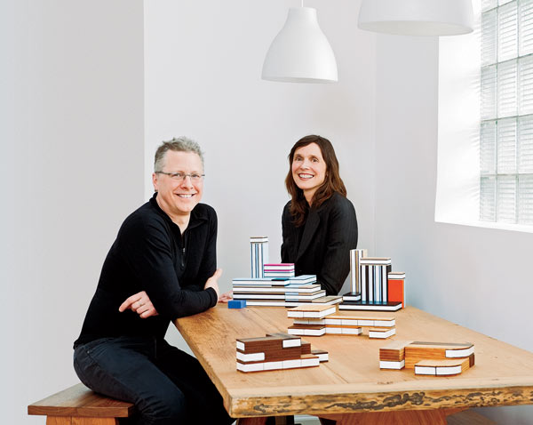 Peter Dunham and Linnea Gits, at a dining table designed and built by Dunham, with Uusi’s Moderne City and (in foreground) Moderne Home block sets
