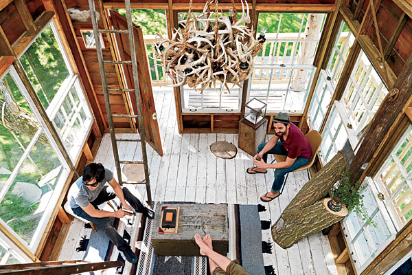 Shaun Owens-Agase (left), Bladon Conner (right), and Peterson (on the sofa) relax in the main cabin. The tree bursts through the floor and out the window on the right; in other spots, it was chopped even with the floor.