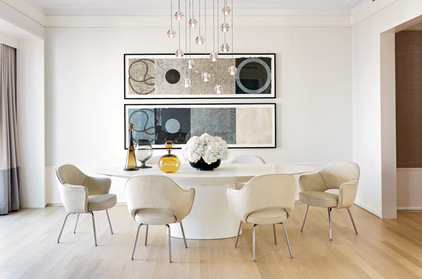 Designer Jessica Lagrange created a softly minimalist tableau with a lacquered pedestal table and Knoll Saarinen chairs on a bare floor and a 14-pendant Bocci chandelier.