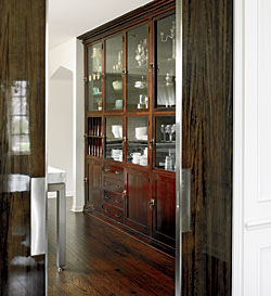 Space-saving pocket doors of heavily lacquered gumwood with stainless steel trim and recessed handles make it possible to close off the kitchen from the front of the house.