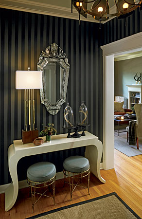 In the foyer of this Edgewater condo, interior designer Sean Cowan and his partner, Eric Silverstrim, alternated two-inch stripes of semigloss black and flat charcoal paint on the walls, creating a glamorous backdrop for a white fiberglass Regency-style console.