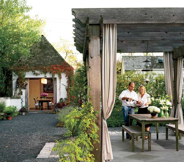 Frank and Becky Ponterio enjoy a glass of red in the pergola. The couple's wine collection is stored in a former carriage house that has been converted to a pour room (at left).