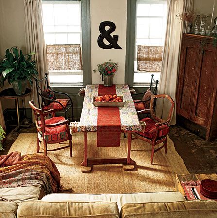 Photo stylist Johanna Lowe created a casual spot for meals in the living room of her Buchanan, Michigan, house by mixing vintage chairs with a table improvised from a door and a pair of sawhorses. One of her favorite finds is the large enameled-metal ampersand between the windows.