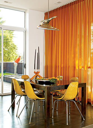 An Italian chrome chandelier marks the spot for the raw steel table in a Wicker Park dining room. Playing off yellow fiberglass shell chairs, the amber semi-sheer panels, which don’t cover the entire span of the windows, can be shifted to follow the sun. Sliding doors open to a huge rooftop deck.