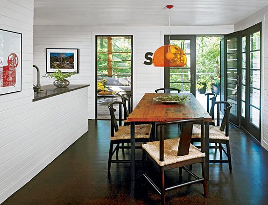 Cork floors, a black-and-white palette, and CaesarStone countertops that mimic honed concrete give this space in a Michiana home a modern edge, while horizontal paneling helps maintain a cozy cottage feel. Glass-paneled doors provide access to the deck and screened porch and also bring in light.