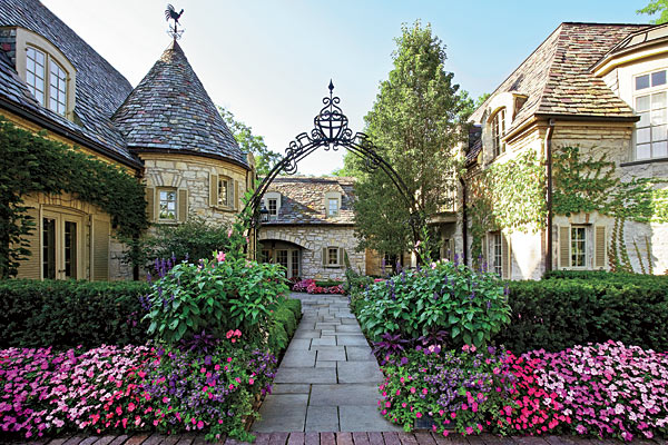 A dry-laid bluestone path leads under a custom iron archway to the front door.