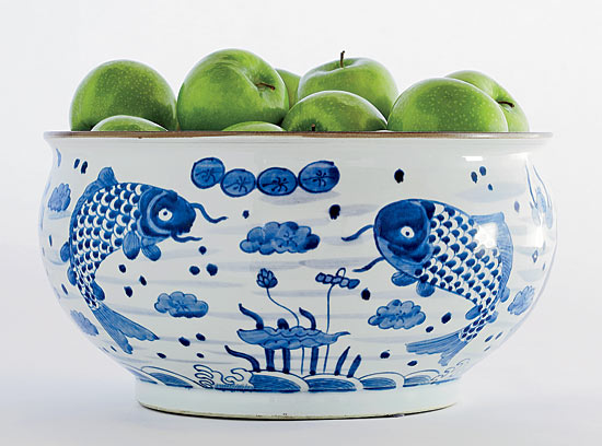 A ceramic bowl filled with green apples