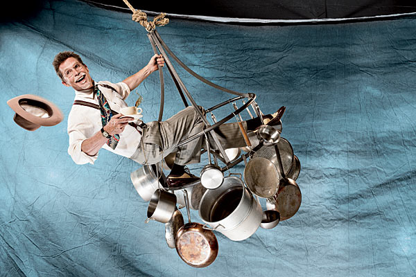 Rick Bayless swinging from a hanging pot rack