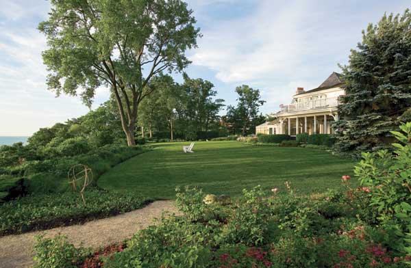 A dry-laid bluestone path leads under a custom iron archway to the front door.