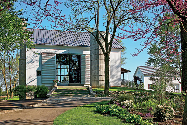 Painted aluminum siding that mimics wood planks and enormous crank-operated sliding doors preserve the barnlike feel. The house next door was built for the homeowner’s daughter.