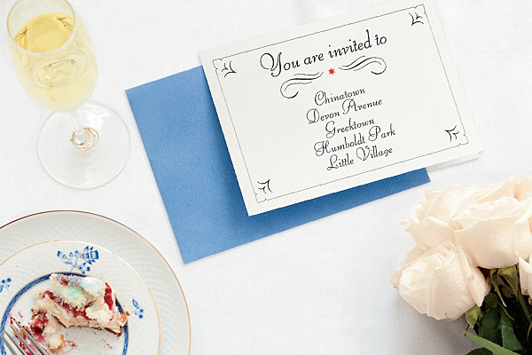 A glass of wine, wedding invitation, flowers, and cake