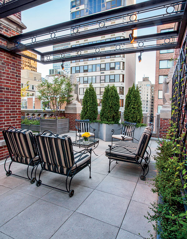 An iron pergola makes the seating area feel more intimate and anchors the lighting and fabric shades.