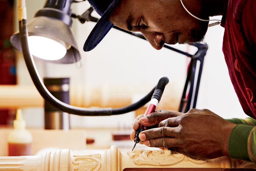 Masudi Mzaliwa uses a compressed-air carving tool to add detail to a column.