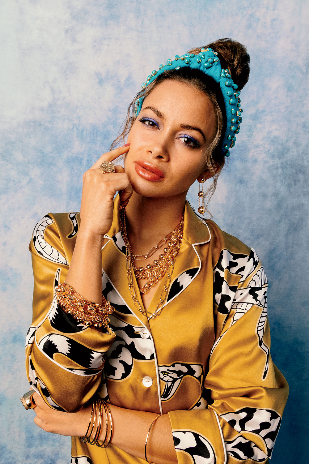 Sarah Gorden wearing silk pajamas, turquoise-embellished candy jeweled headband, Tiffany HardWear 18-karat gold earrings, 22-karat gold-plated ring, 22-karat gold-plated circle ring, Nest 22-karat gold-plated necklace, 22-karat gold-plated bracelet, and Nest 22-karat gold-plated bangles.