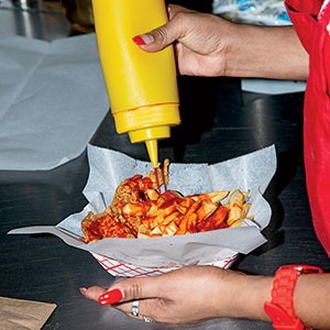 Adding mild sauce to an order of wings and fries