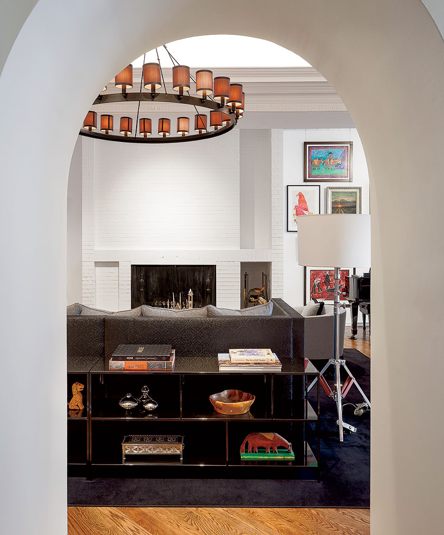 A Restoration Hardware carriage-wheel chandelier  illuminates the owners’ outsider art collection, which ranges from bird feeders to mixed-media paintings.