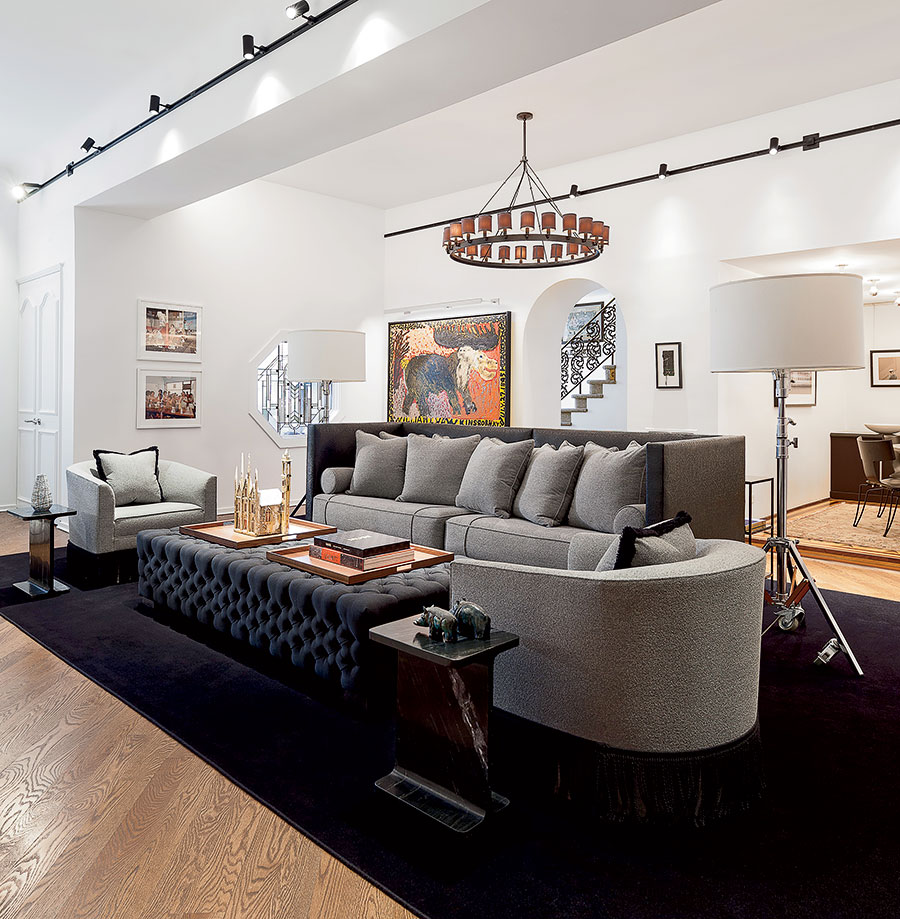 The sofa in the living room was made by Todd Haley for the clients’ previous home; he had it resized to fit the new space. Light from an octagonal window softens the masculine feel of reupholstered vintage side chairs, a custom ottoman, and CB2 marble side tables.