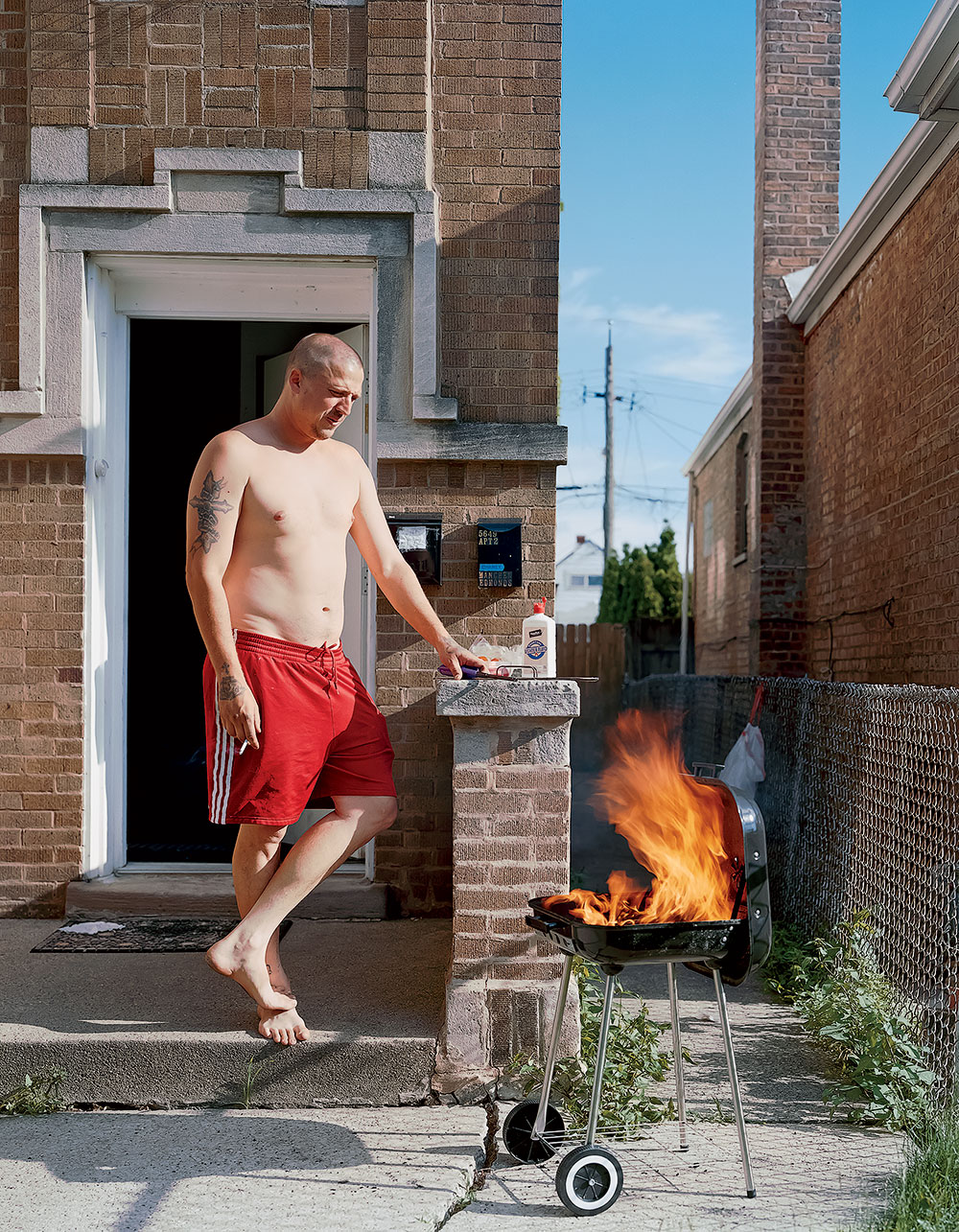 A man barbecuing in front of his home.