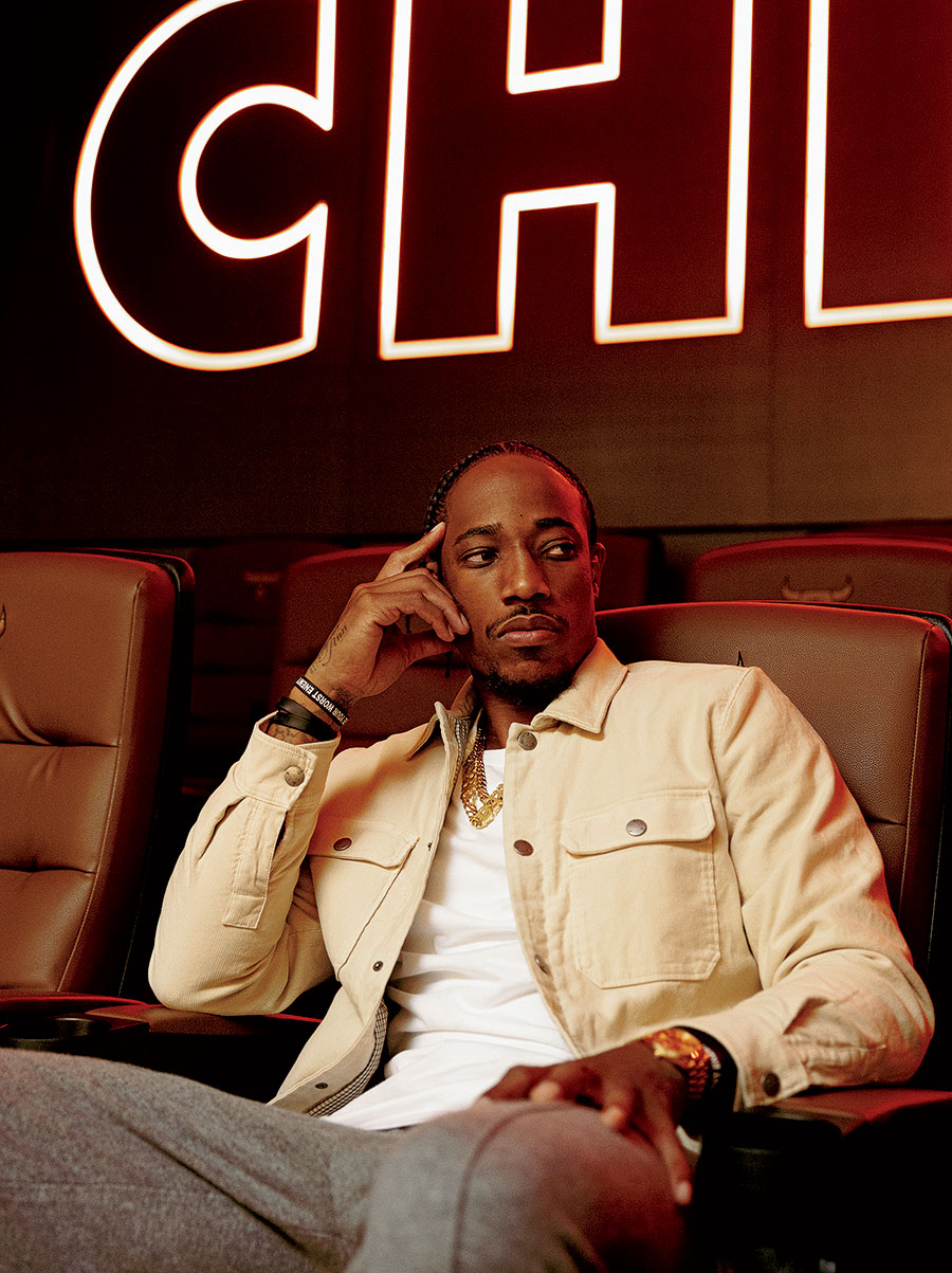 DeRozan seated in front of a "Chicago" neon sign