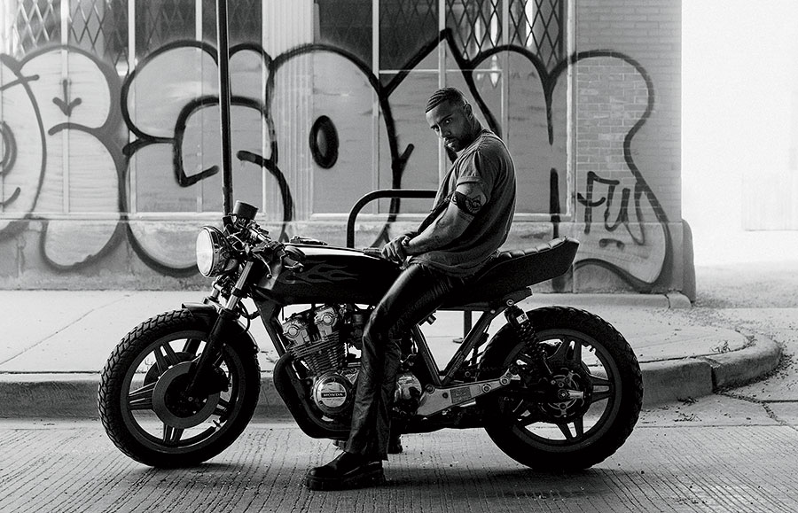 A black and white photo of Vic Mensa sitting on a motorcycle