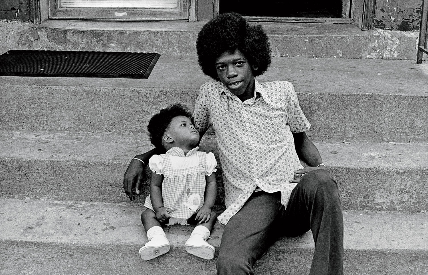 A 1974 photo of a young man and a baby sitting on the steps of a Chicago Avenue building.