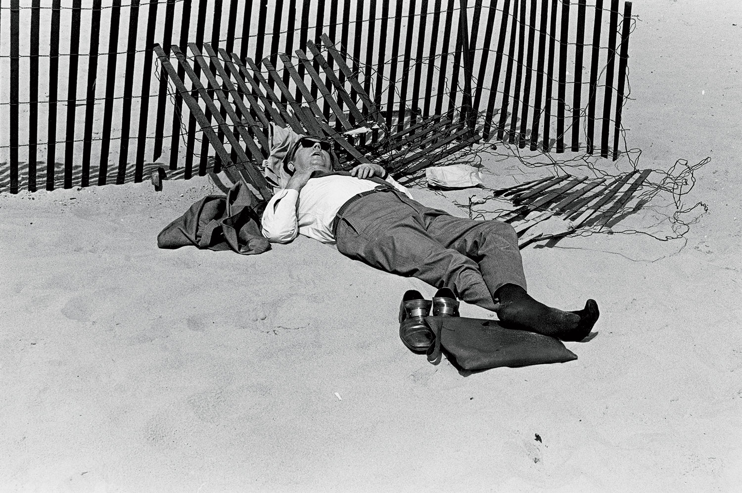 A 1971 photo of a well-dressed man asleep by the snow fence at Oak Street Beach.