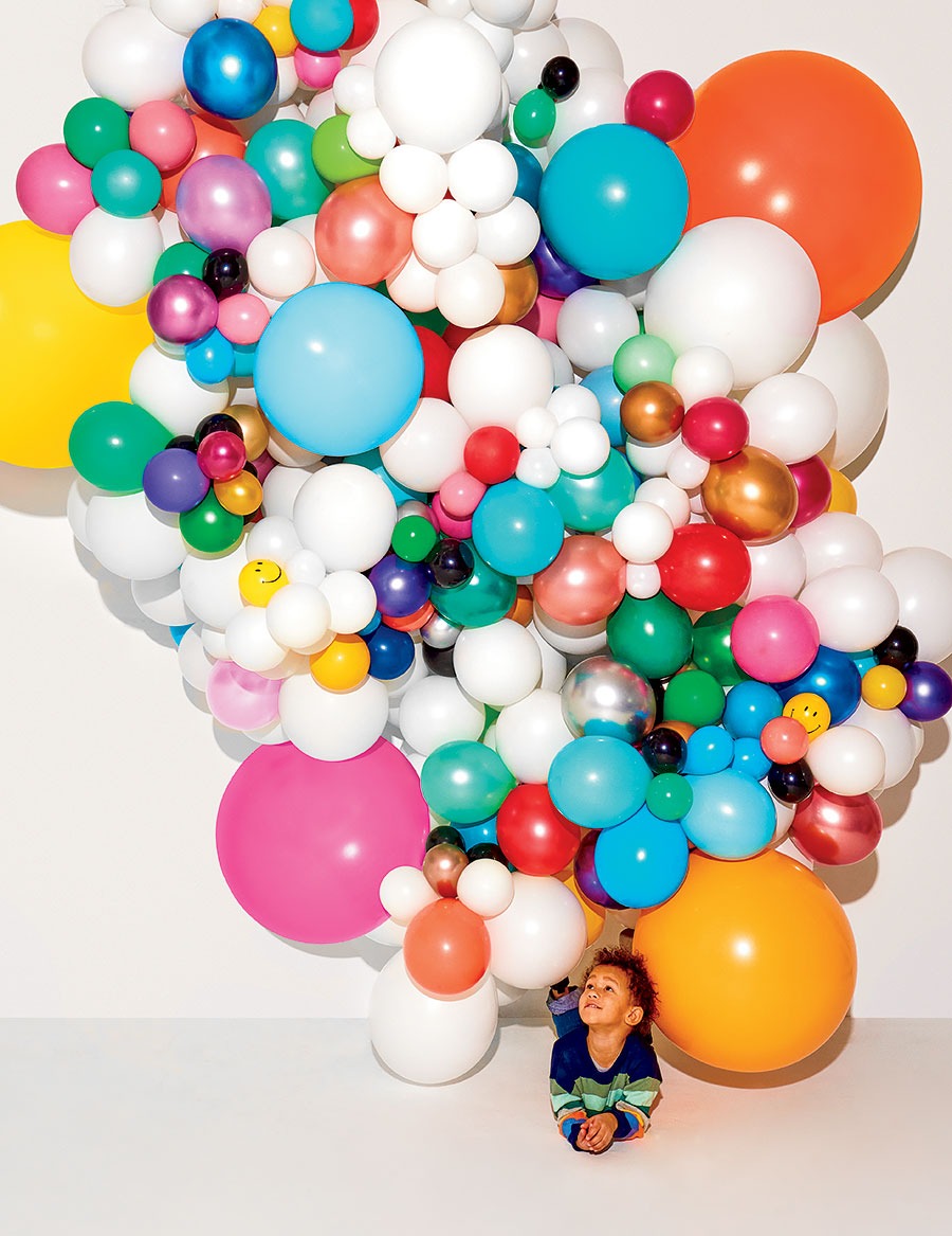 A child lying beneath a mass of balloons from Luft Balloons
