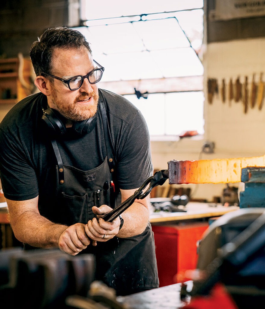 Bladesmith Sam Goldbroch puts the metal he forged into a vise 