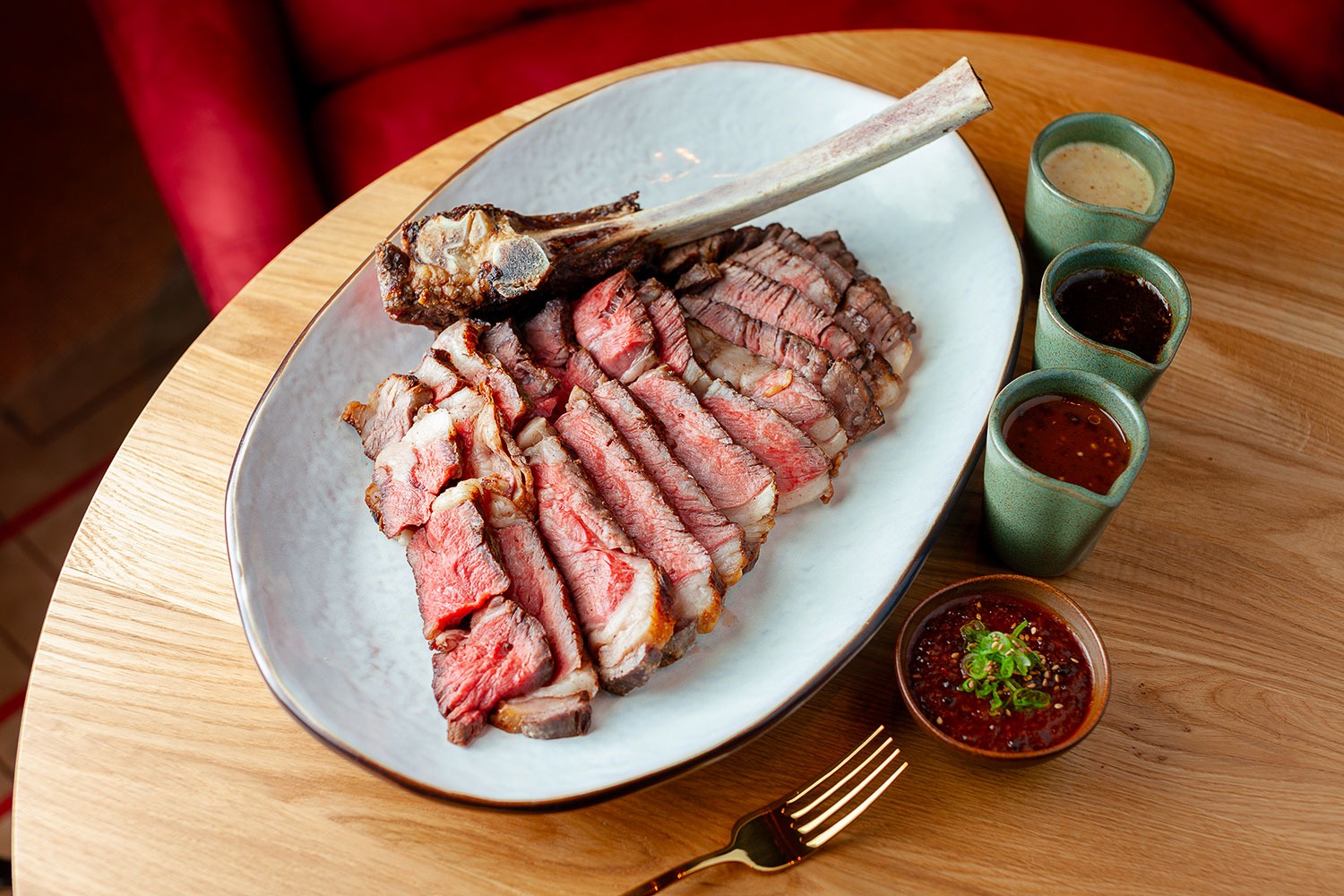 A sliced steak with various sauces at Perilla Steak