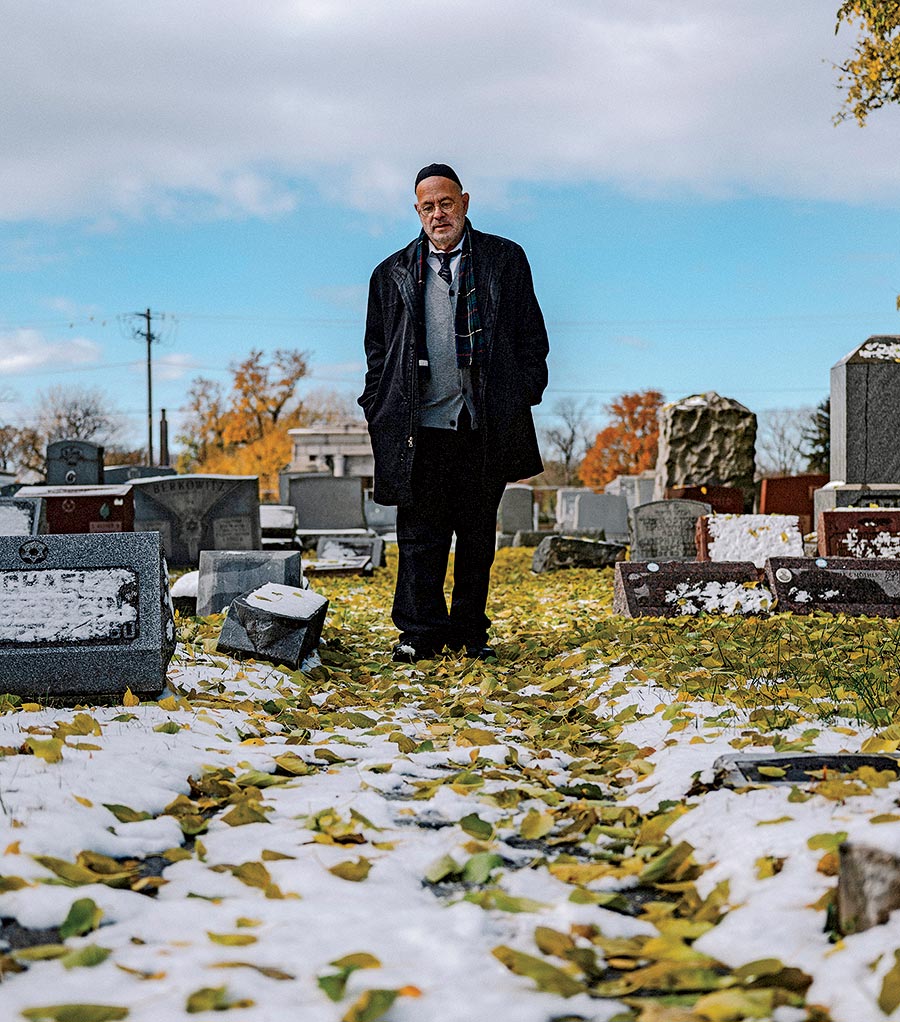 Shlomo Tenenbaum walking among the headstones in a cemetery
