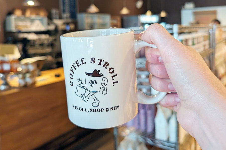 a hand holding a mug that says Coffee Stroll