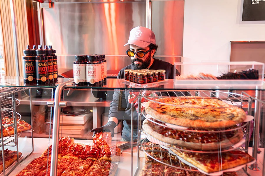A worker preparing to serve pizza at Professor Pizza