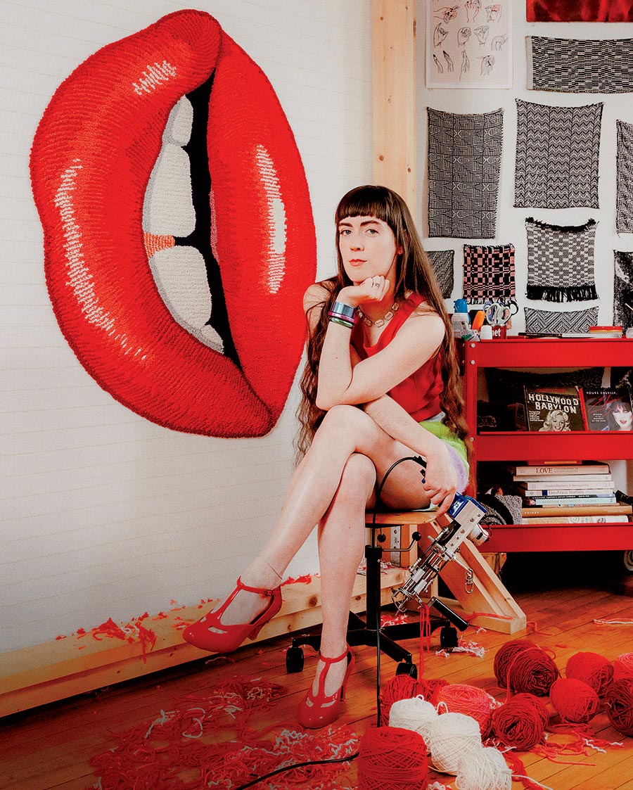 Moira Quinn sitting next to a red lips-shaped rug